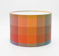 Autumn Squares lampshade — warm red and gold geometric check on a cotton drum shade.