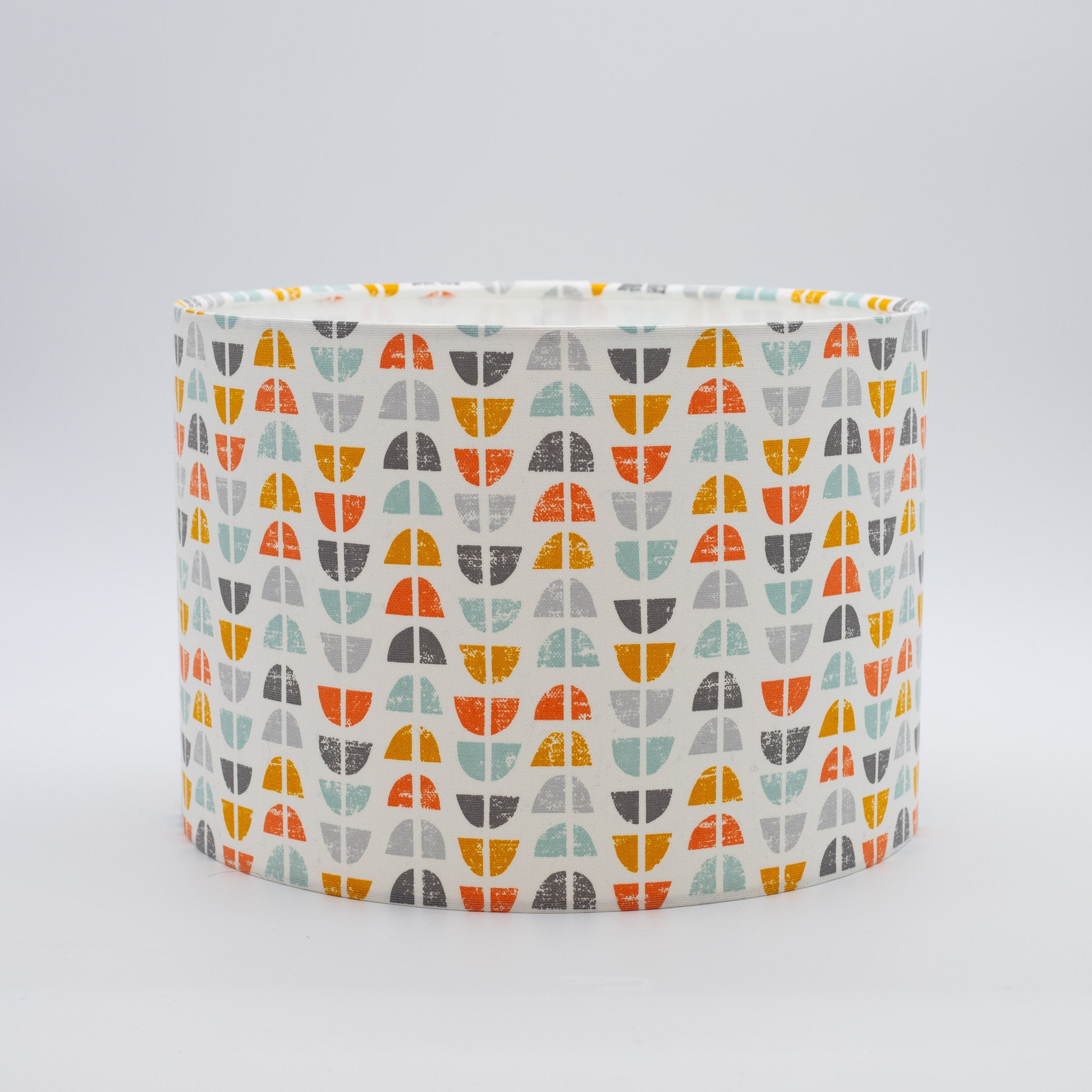 Half Moon Spice lampshade — warm orange and red half-moon pattern on a cotton drum shade.