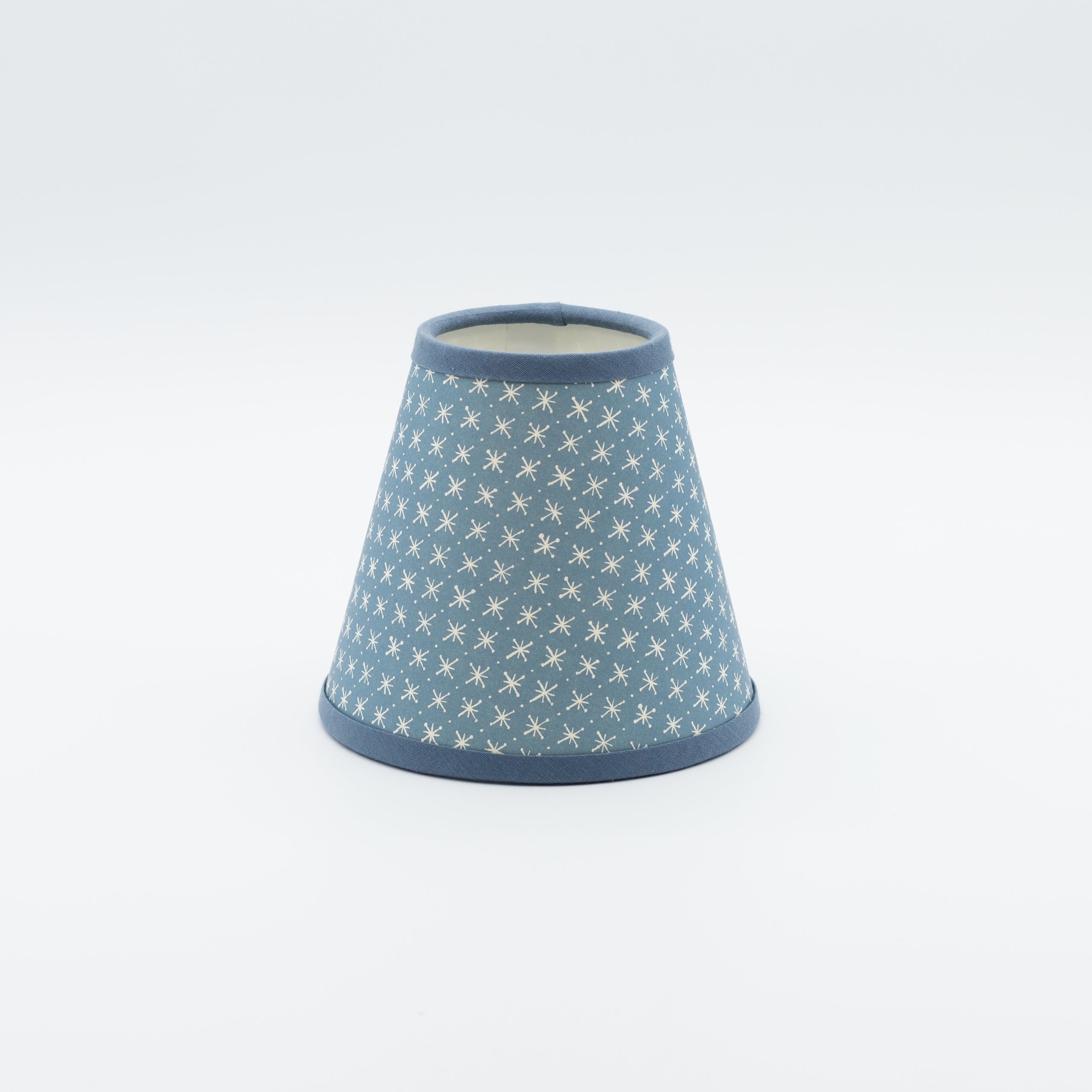 Little Stars lampshade in denim blue — small scattered star print on a handmade conical paper shade.