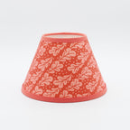 Quercus lampshade in pomegranate red — oak-leaf pattern on a handmade conical paper shade.
