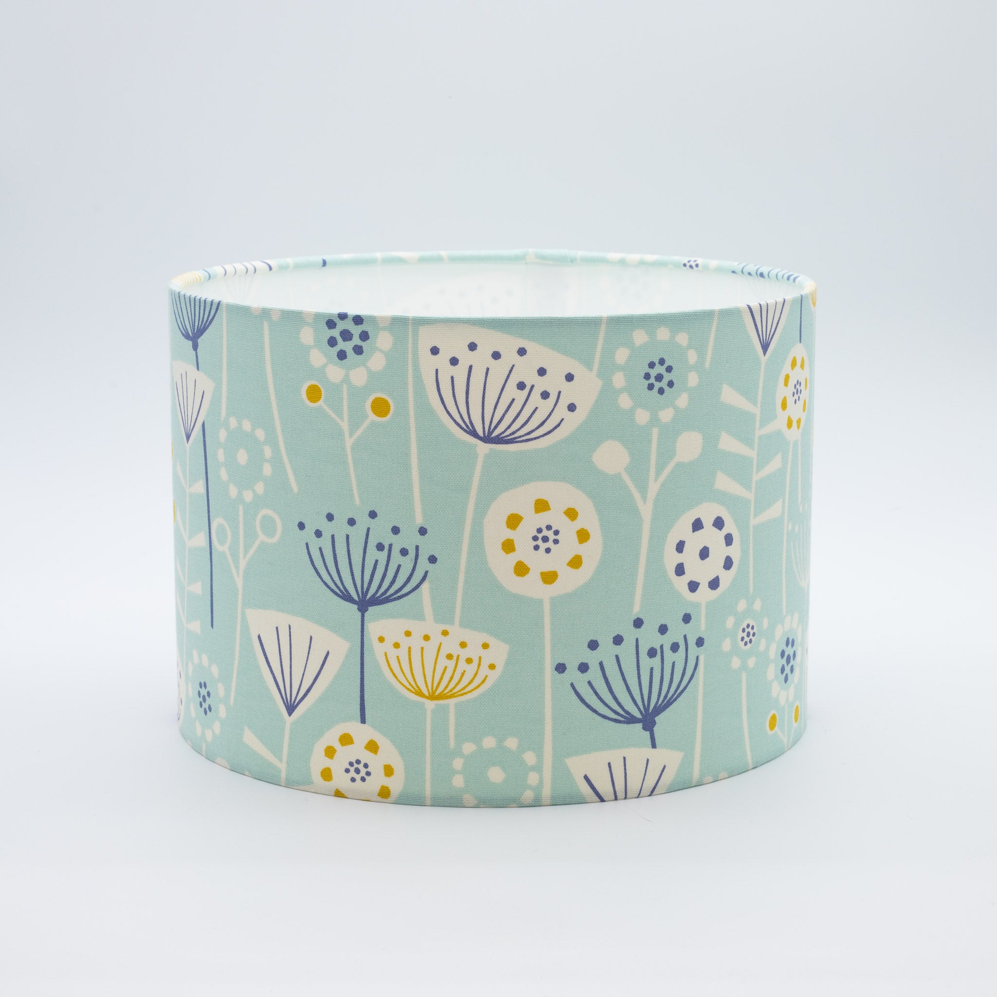 Seedheads lampshade in soft teal — botanical seedhead pattern on a cotton drum shade.